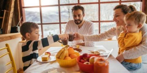 Foto de una familia joven conformada por padre, madre, niño y niña, desayunando